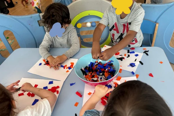 Groupe d'enfants crèche les bébés explorateurs collent des papiers colorés
